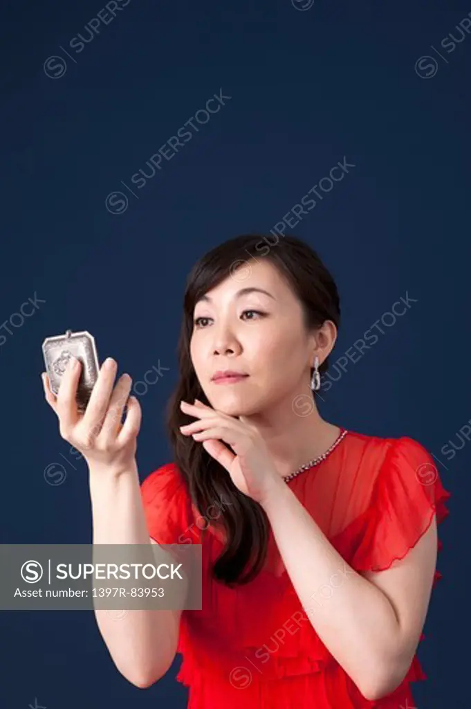Mature woman holding mirror and looking away