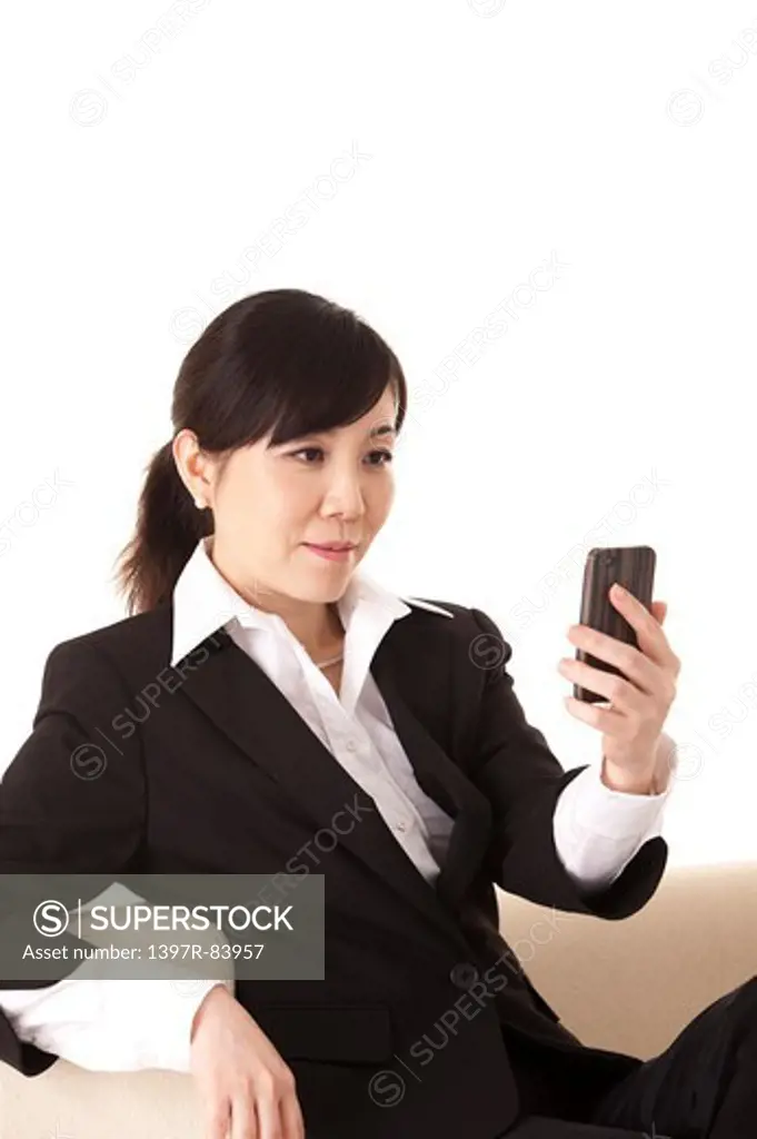 Businesswoman holding mobile phone and looking away with smile