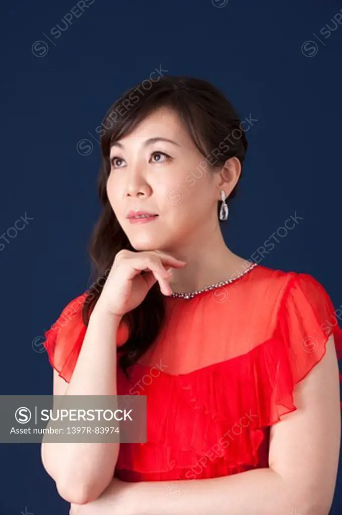 Mature woman looking up with hands on chin