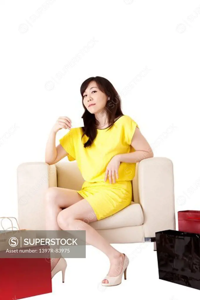Mature woman sitting on sofa with shopping bags