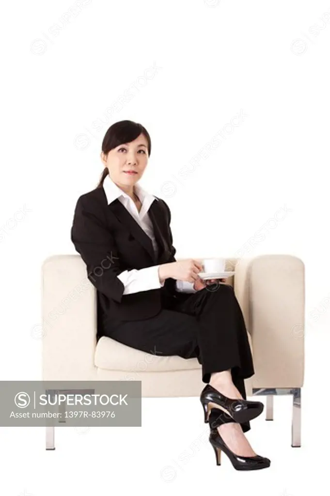 Businesswoman sitting on sofa and holding coffee cup