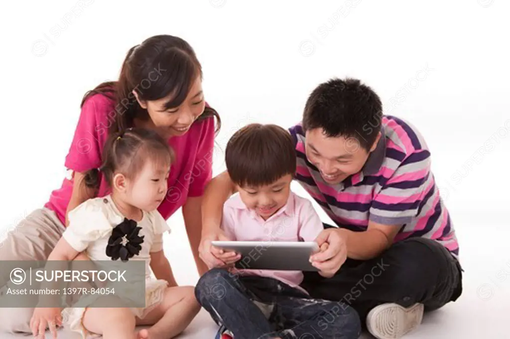 Family with two children sitting and playing pad together
