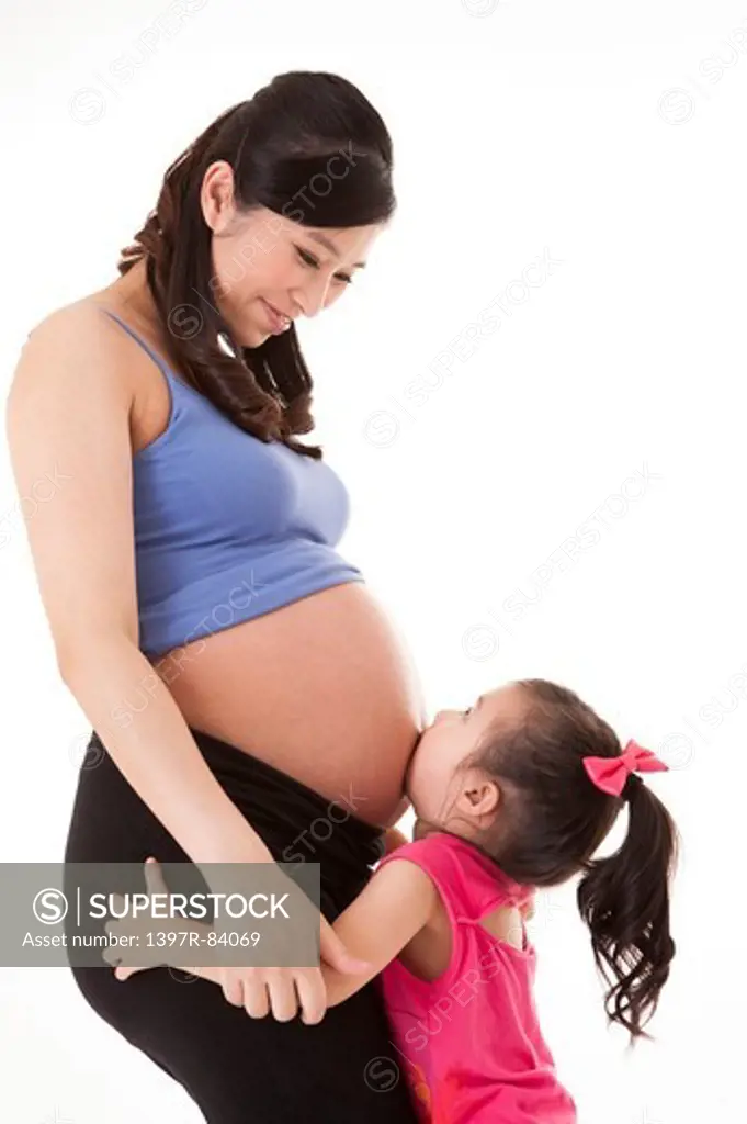 Daughter kissing mother's abdomen
