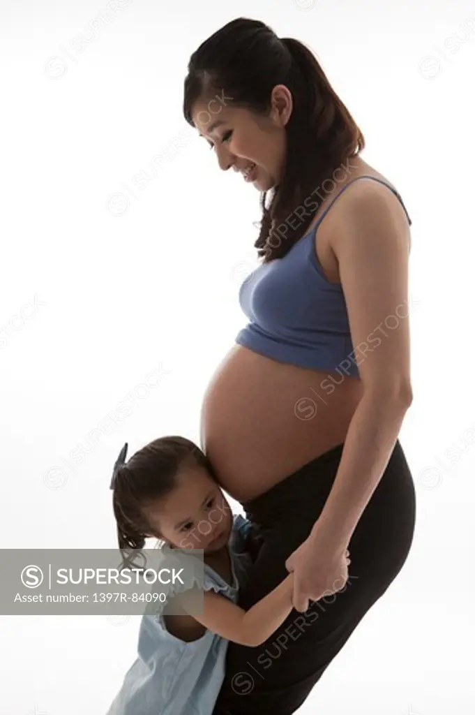 Pregnant mother and daughter holding hands together