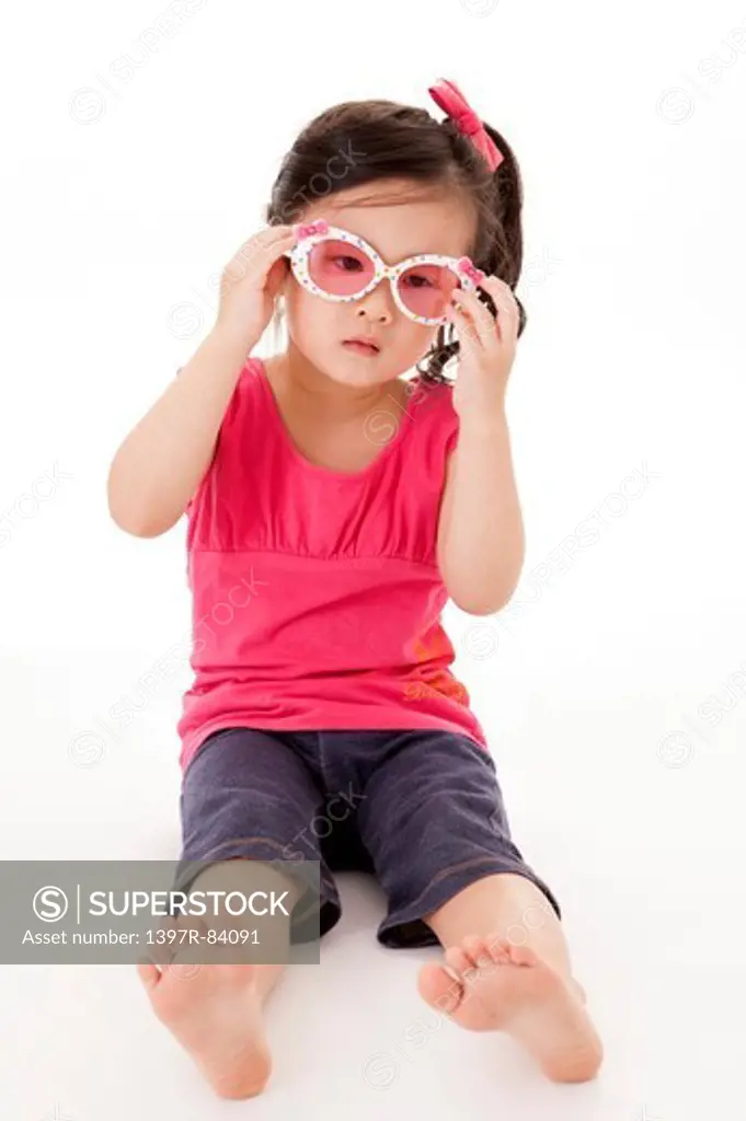 Little girl sitting and holding sunglasses