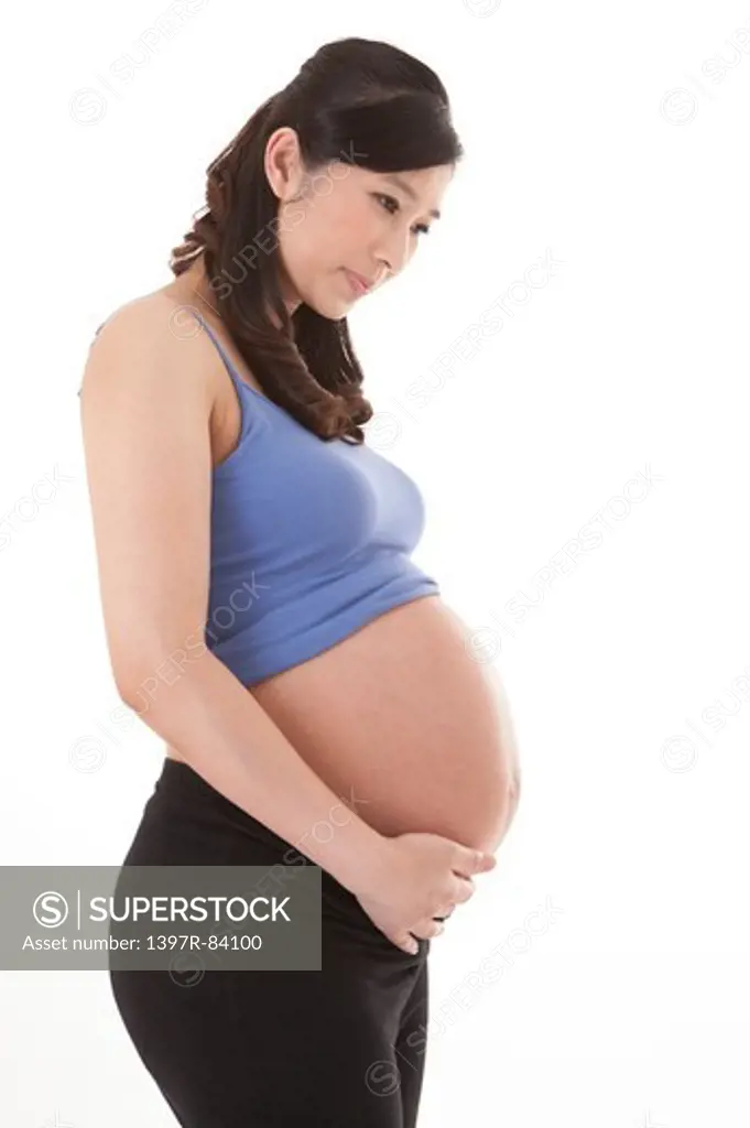 Pregnant woman standing and holding abdomen