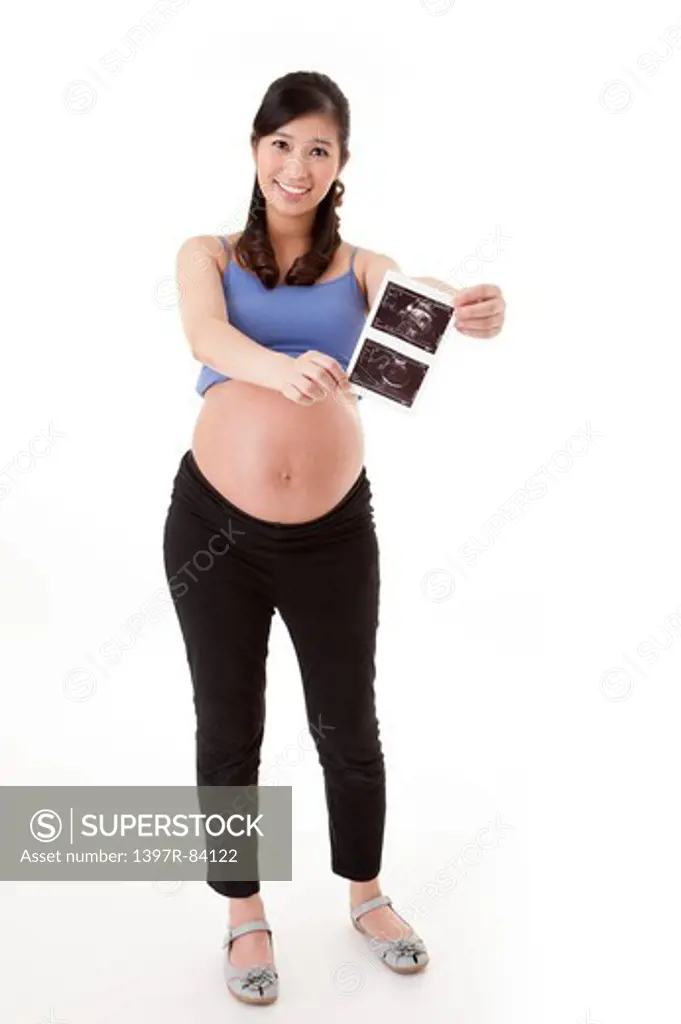 Pregnant woman holding image and smiling at the camera