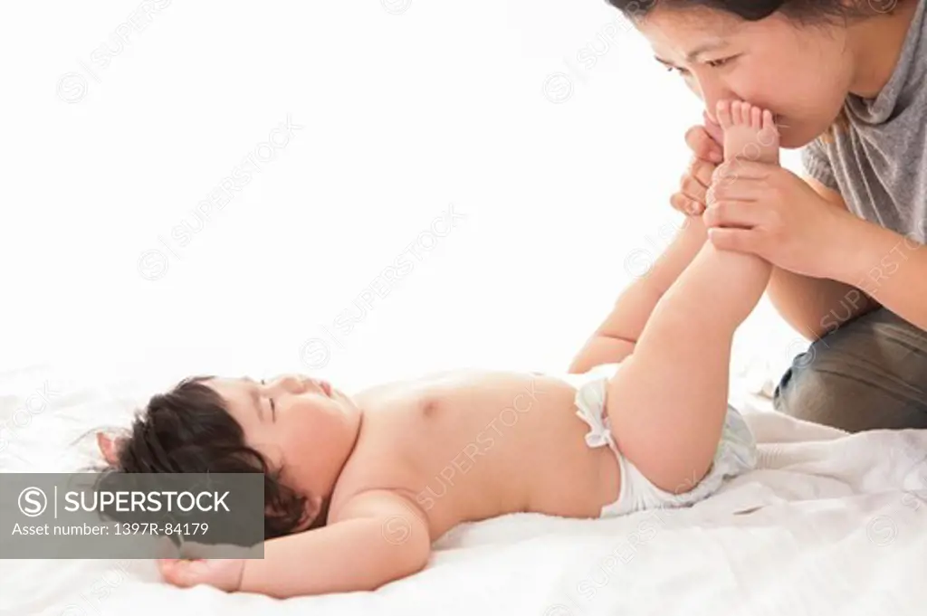 Mother kissing baby girl's feet