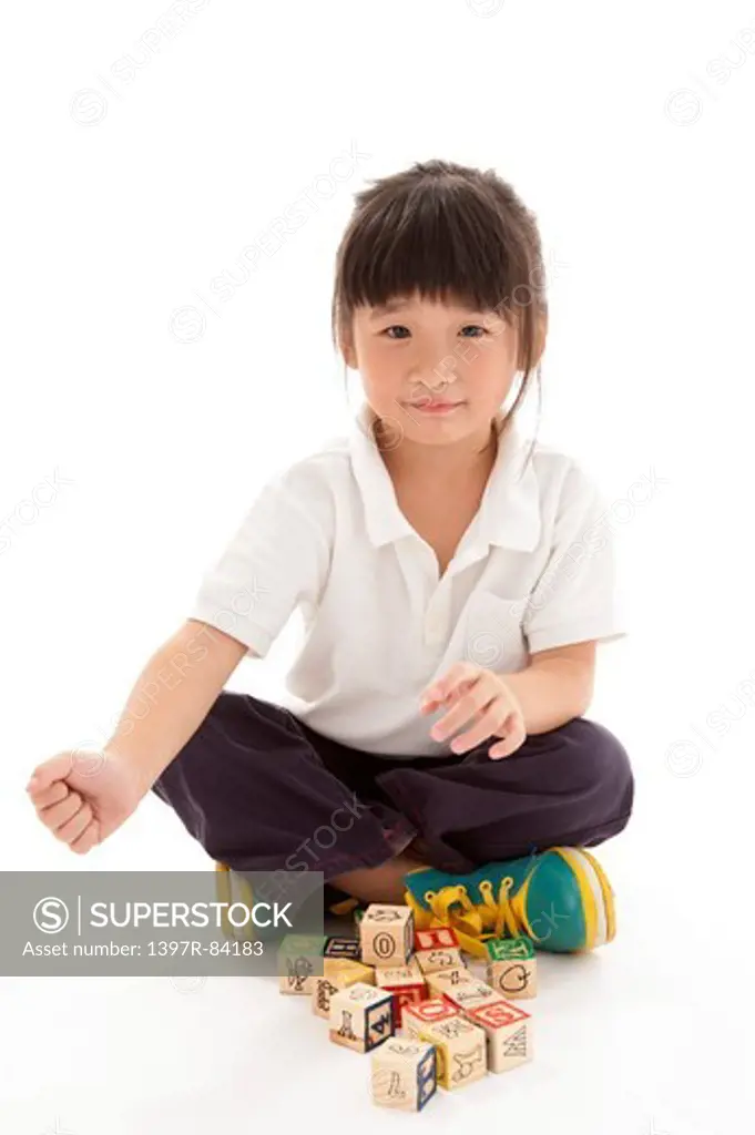 Girl sitting on floor with legs crossed, playing with toys