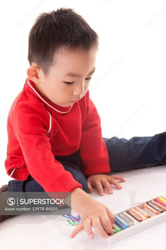 One Boy sitting and holding crayon
