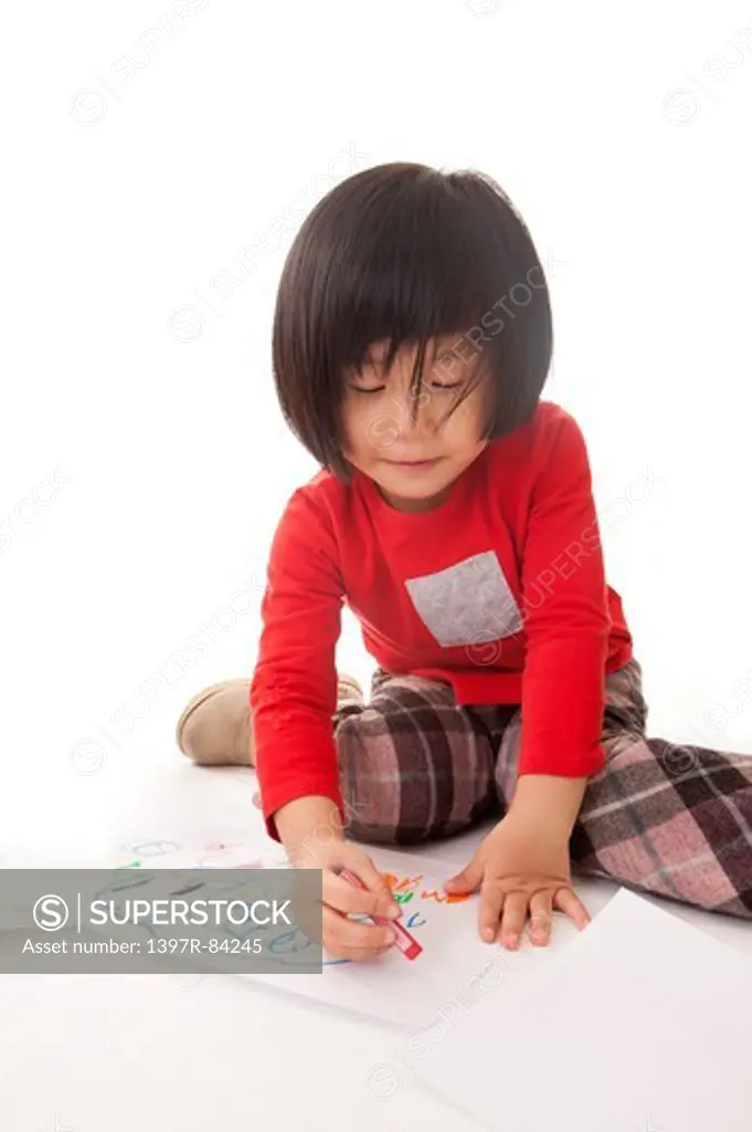Girl looking down and drawing with crayon