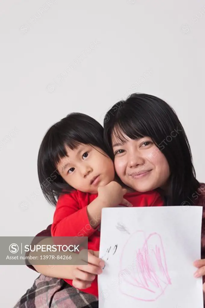 Mother bonding with girl and holding painting with smile