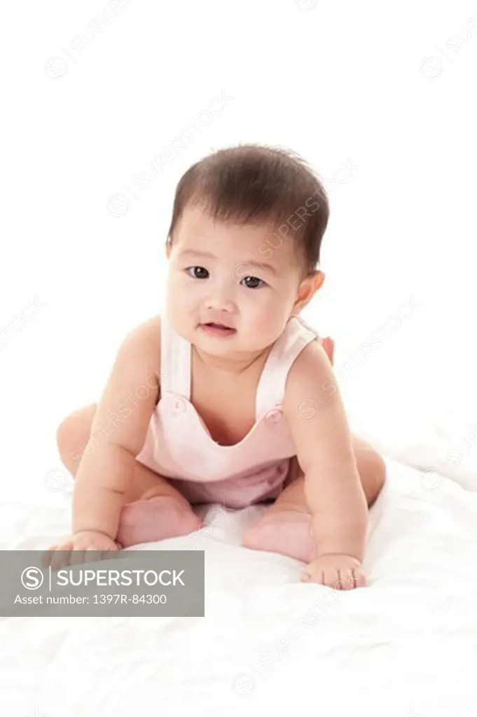 Baby girl sitting on sheet