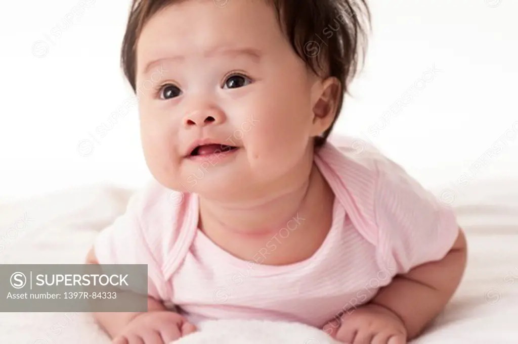 Baby girl crawling on sheet and smiling