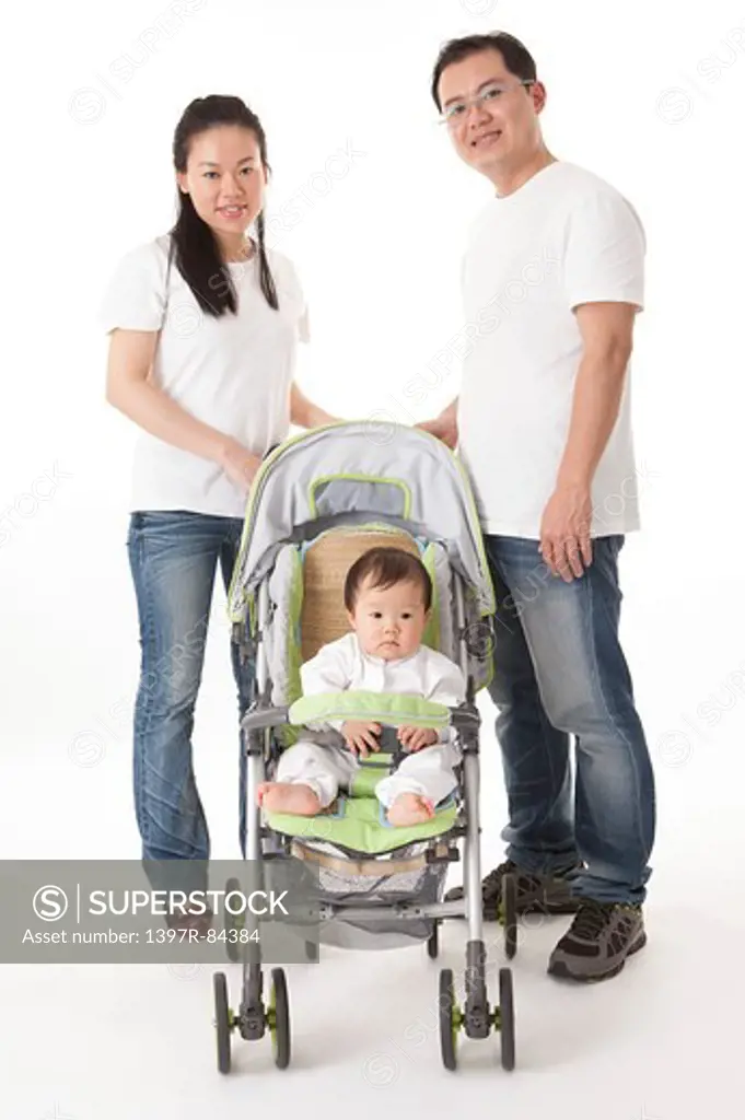 Family with one child standing with baby carriage and smiling at the camera