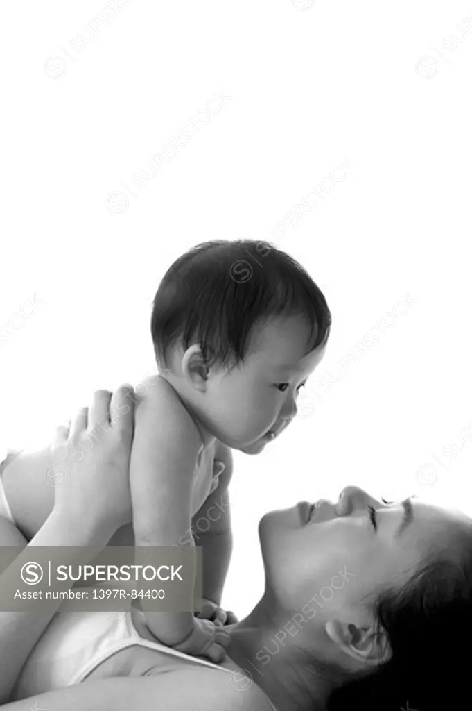 Mother lifting baby girl with eyes closed