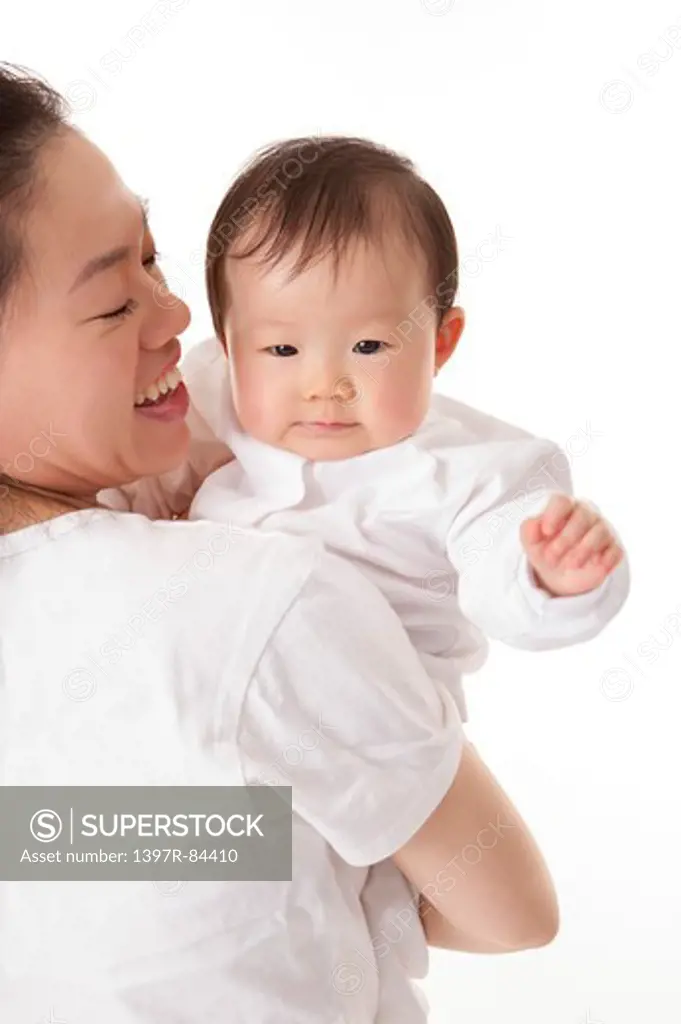 Mother embracing baby girl and smiling happily