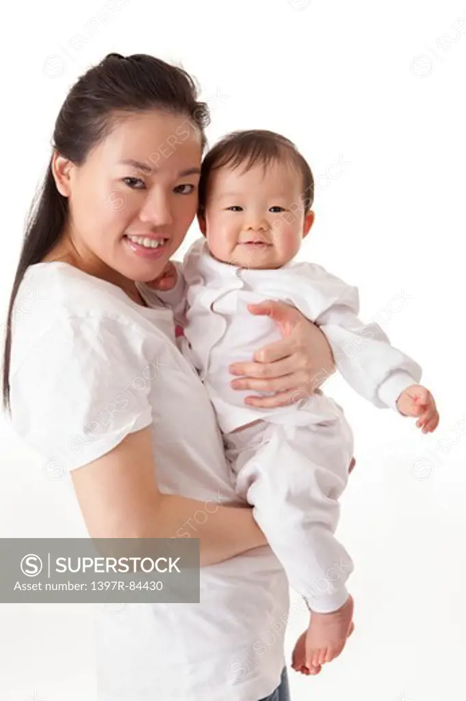 Mother embracing baby girl and smiling at the camera
