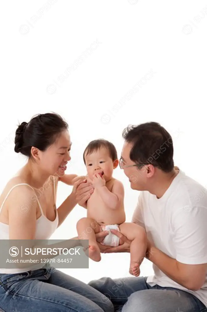 Family with one child embracing baby girl together and looking away with smile