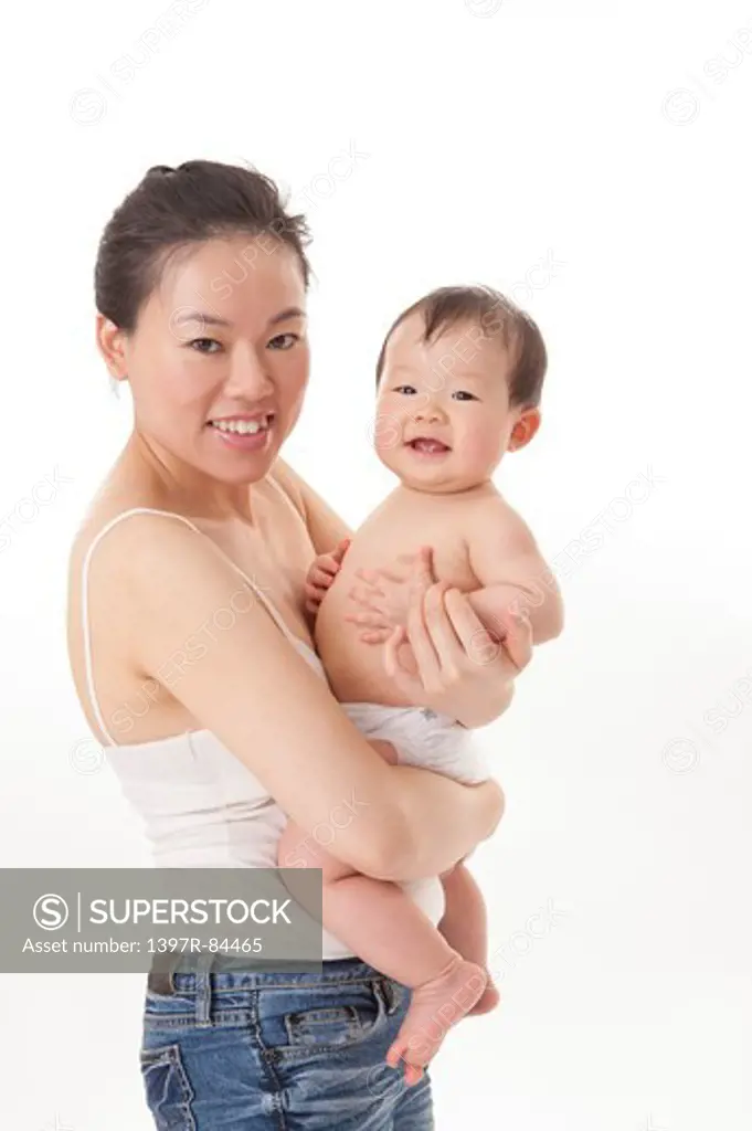 Mother embracing baby girl and smiling at the camera