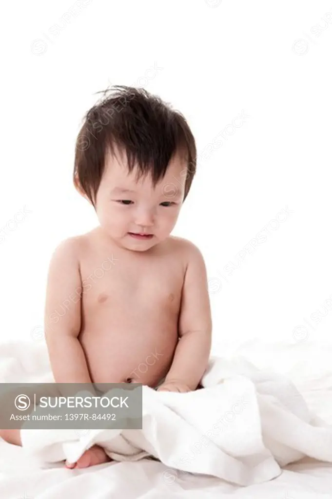 Baby girl sitting in bed with bath towel