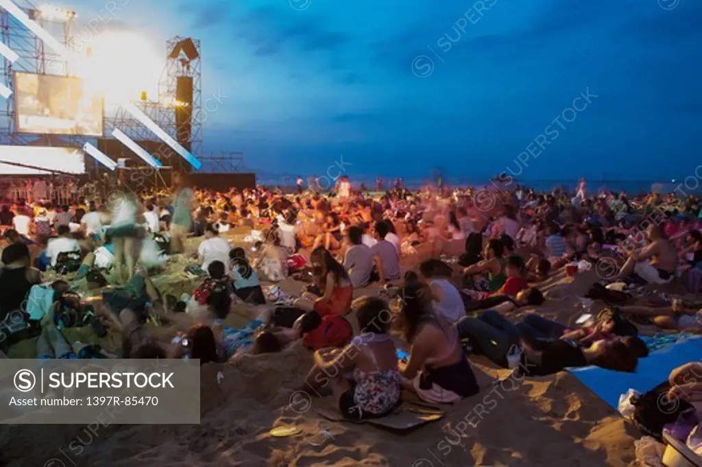 Audience sitting on beach in a popular music concert
