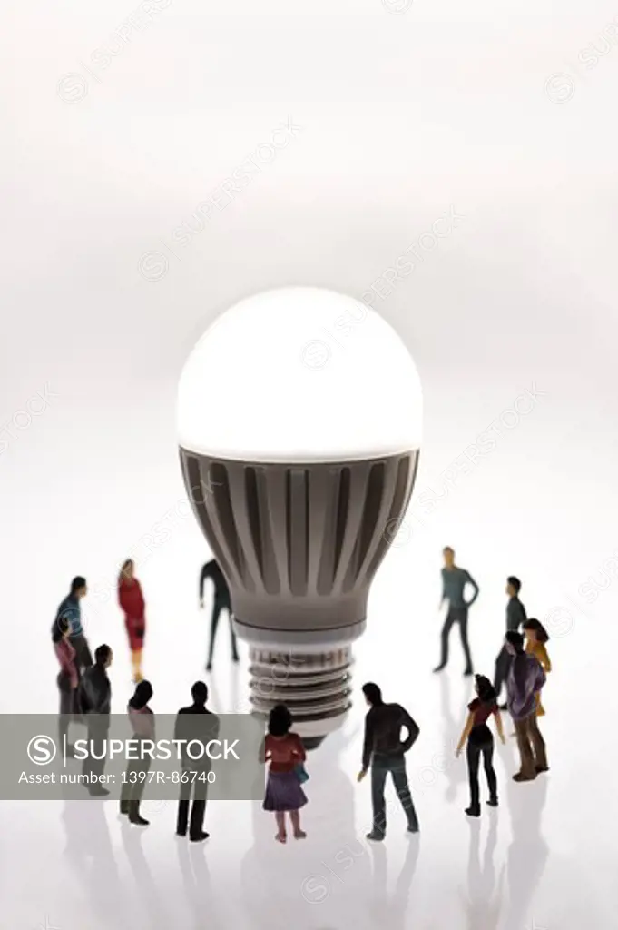 Illuminated light bulb being surrounded by figurines