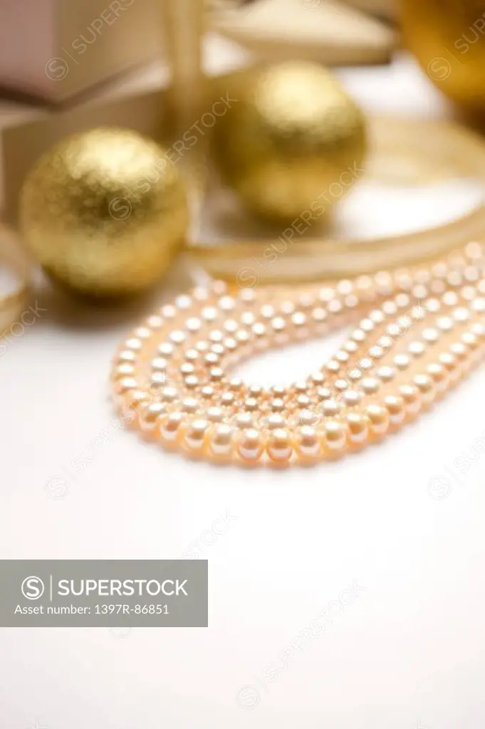Pearl necklace with golden balls in the background