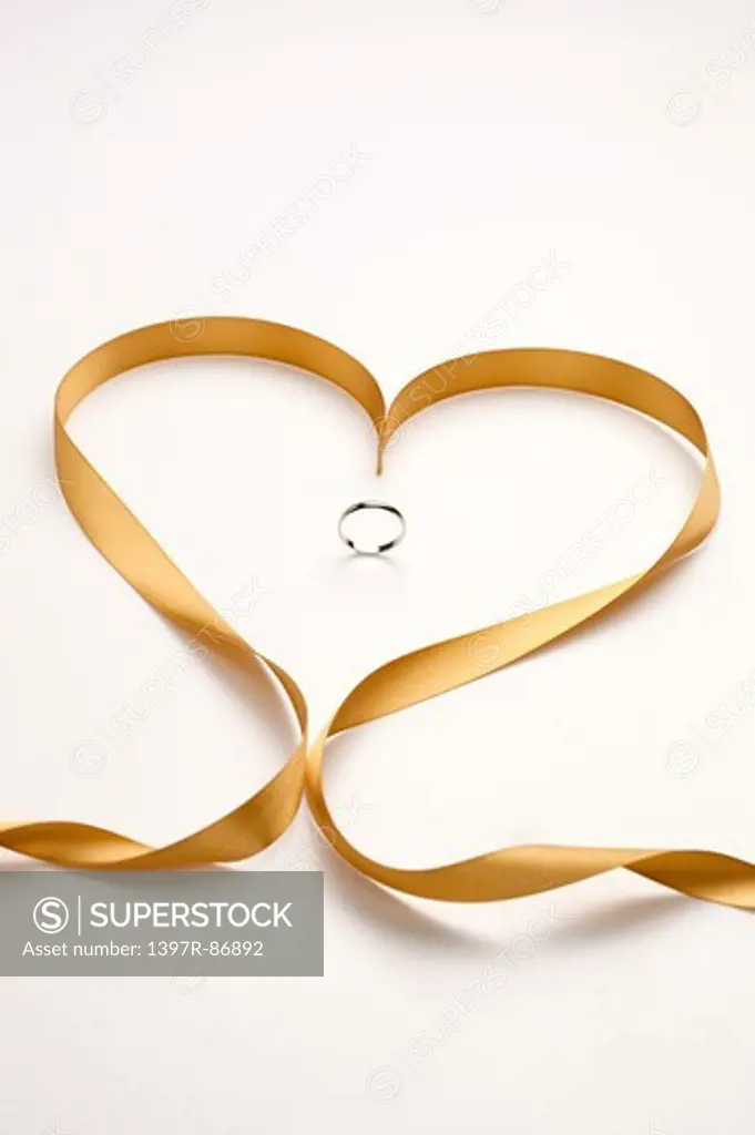 Ring in the middle of heart shaped golden ribbon