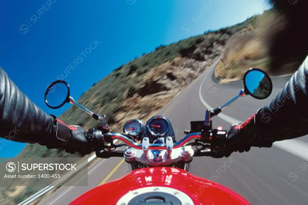 Close-up of a person's hands on a motorcycle's handlebars
