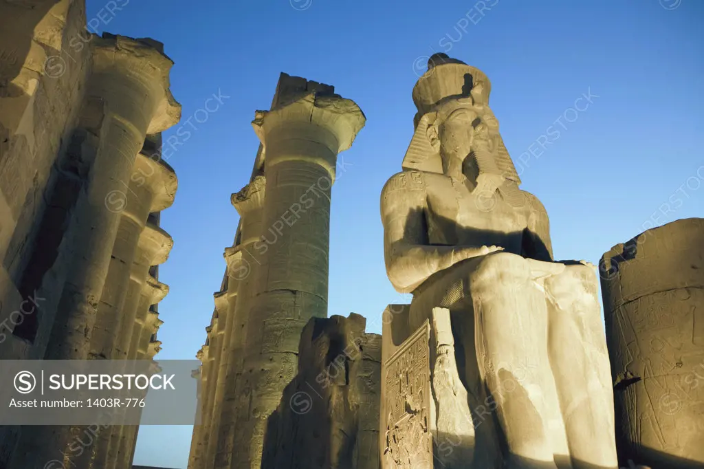 Egypt, Luxor, Luxor Temple, Colossal Seated Statue of Ramses II and Colonnade of Amenhotep III at dusk
