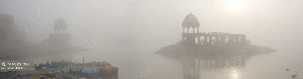 India, Rajasthan, Jaisalmer, Panorama view of morning sun and fog at 14th century man-made Gadisar Lake
