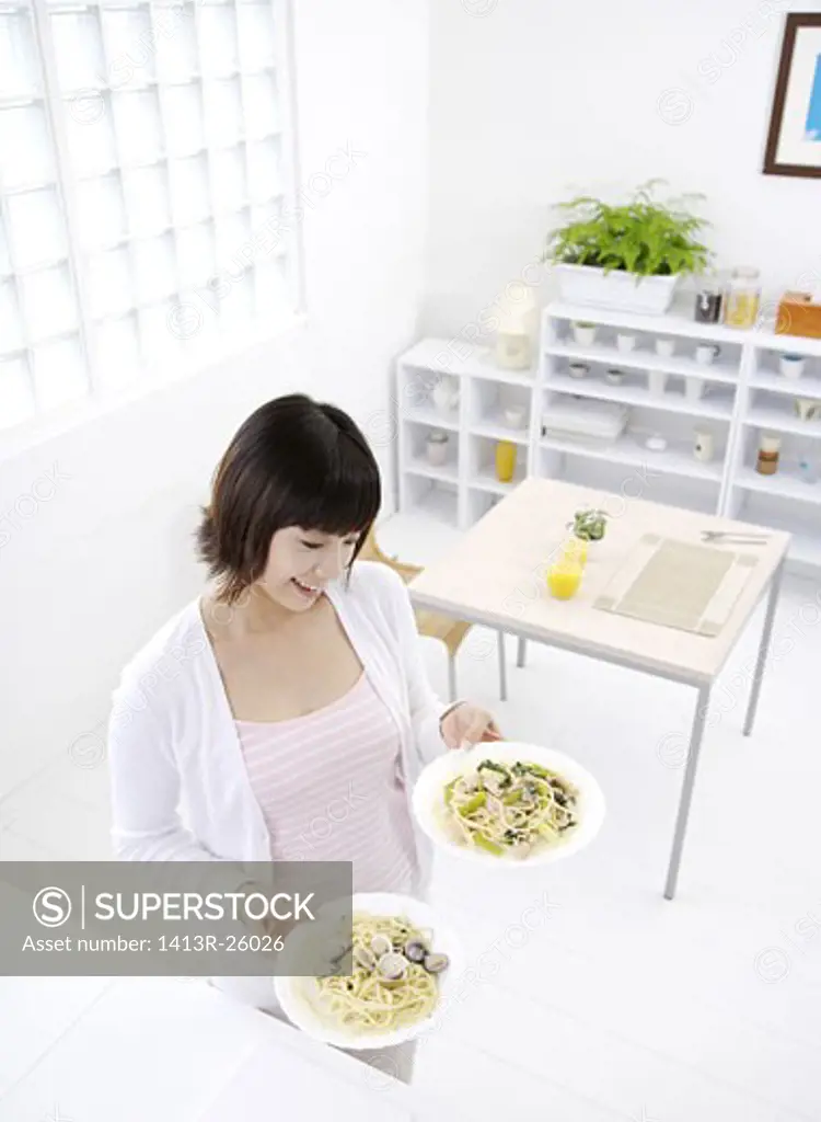 Young woman holding dishes, smiling, elevated view