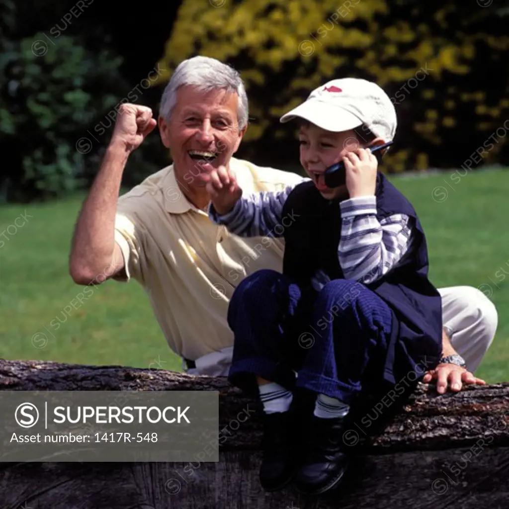 Portrait of a grandfather with his grandson talking on a mobile phone