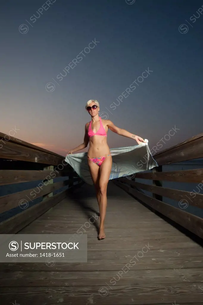USA, Florida, Portrait of woman waling on broadwalk at beach, dusk