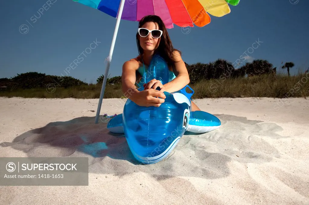 USA, Florida, Portrait of young woman playing with Inflatable whale on beach