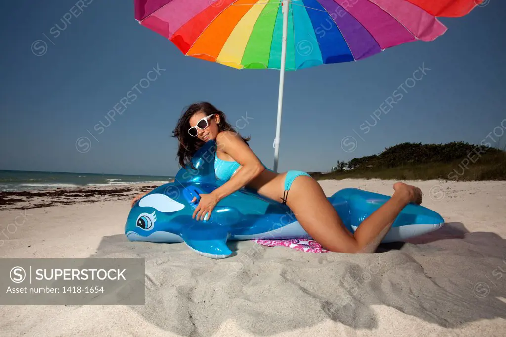 USA, Florida, Portrait of young woman playing with Inflatable whale on beach