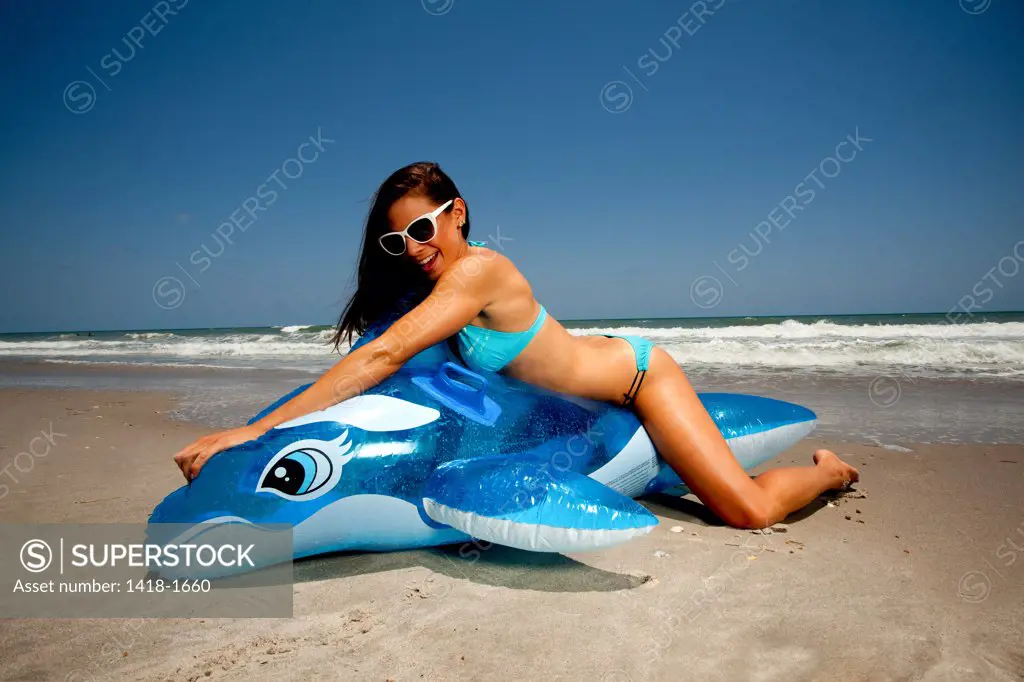 USA, Florida, Young woman playing with Inflatable whale on beach
