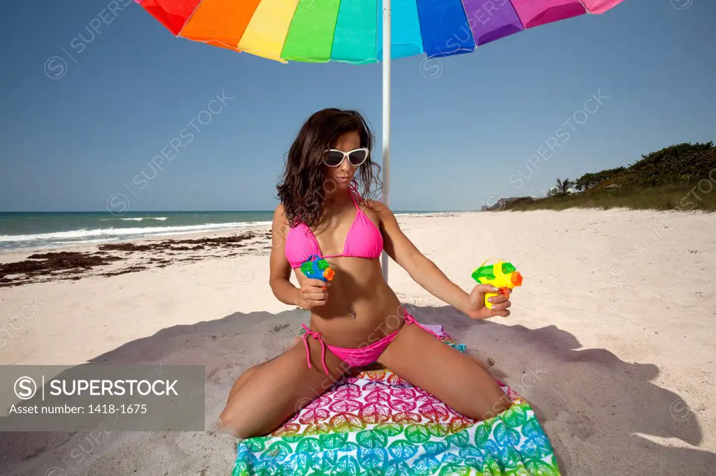 USA, Florida, Young woman playing with squirt guns at beach