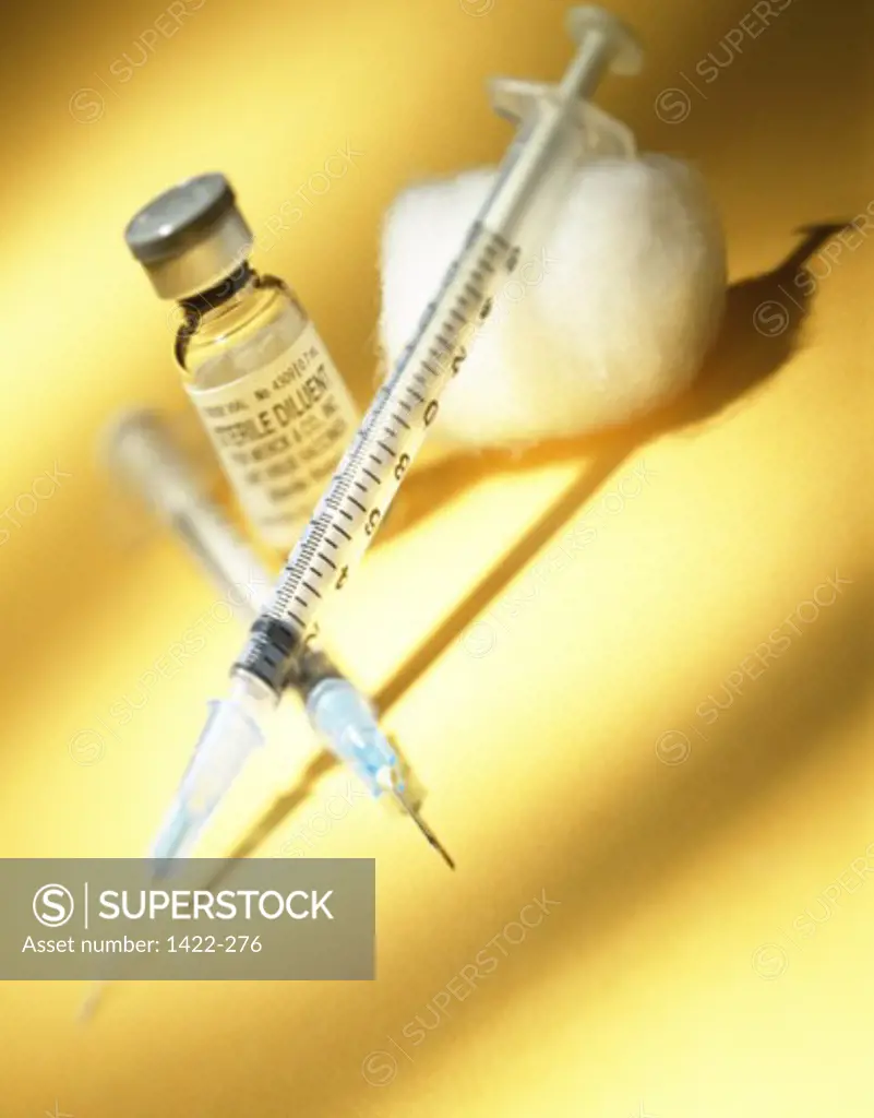 Close-up of two syringes with a vial and a cotton ball