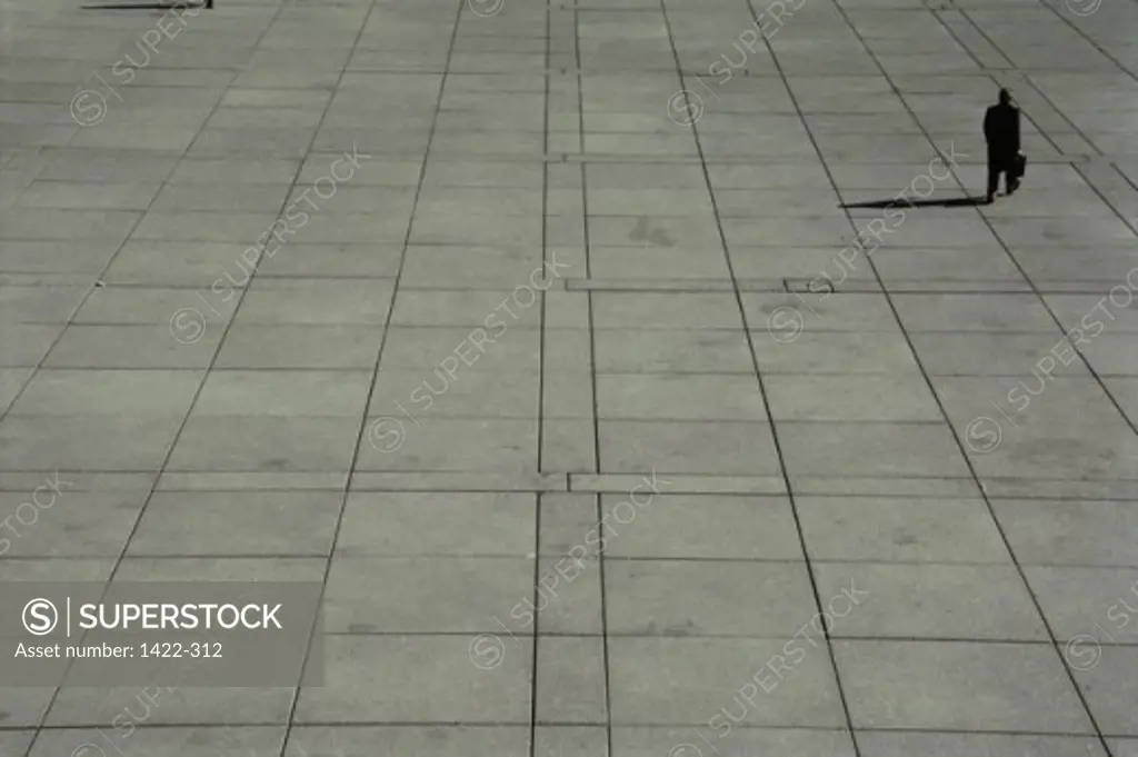 High angle view of a businessman walking on a concrete courtyard