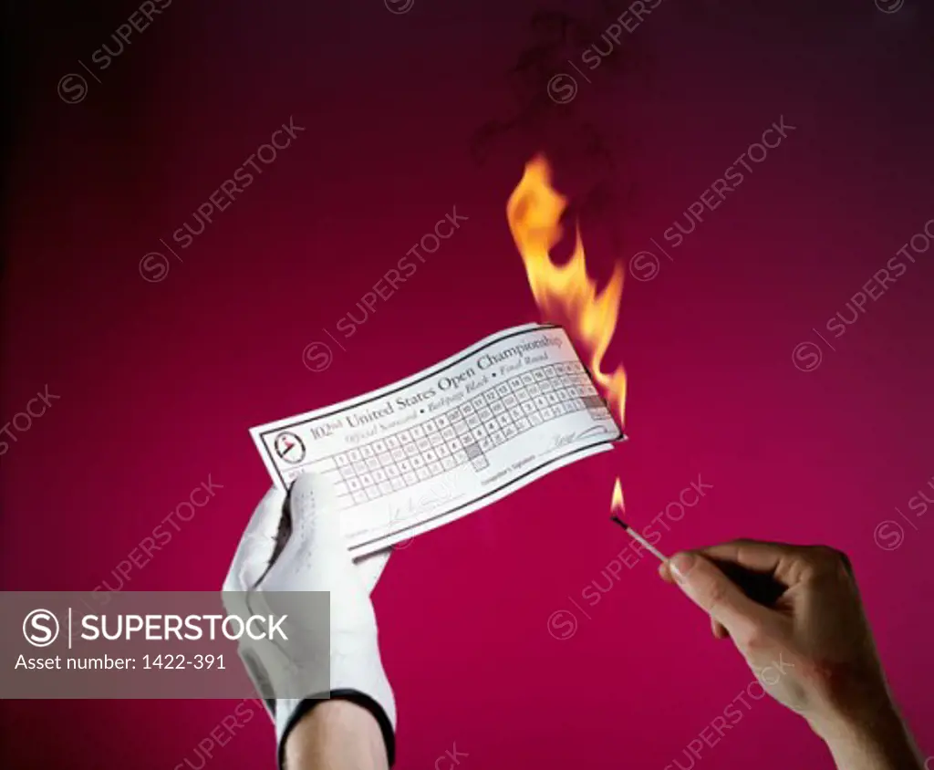 Person setting fire to a golf score sheet