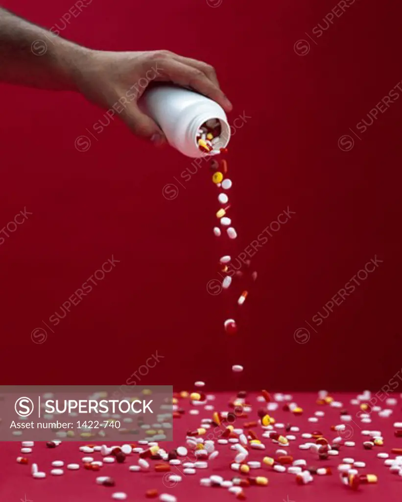 Close-up of a human hand pouring pills from a bottle
