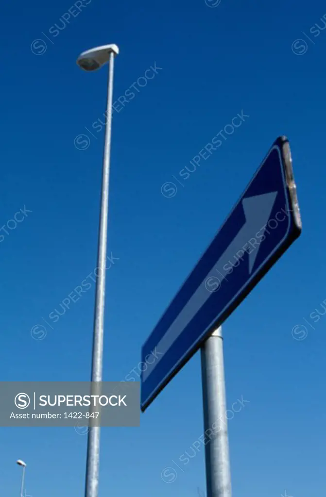 Low angle view of a directional sign near a street light