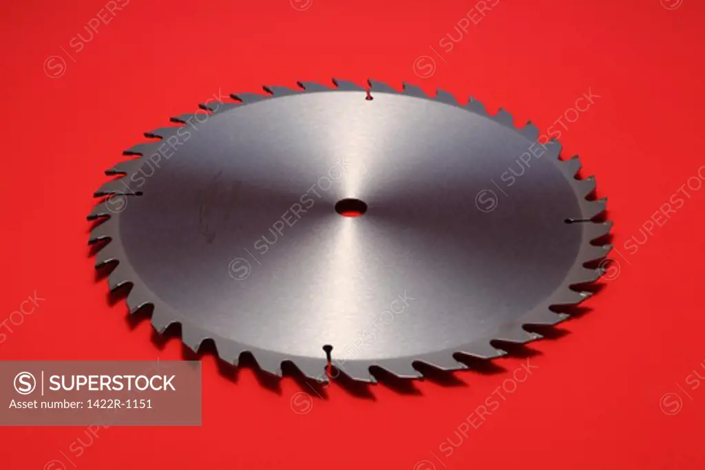 Large circular metal blade with sharp teeth on red background