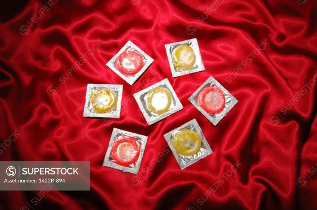 Seven condoms on red satin sheets