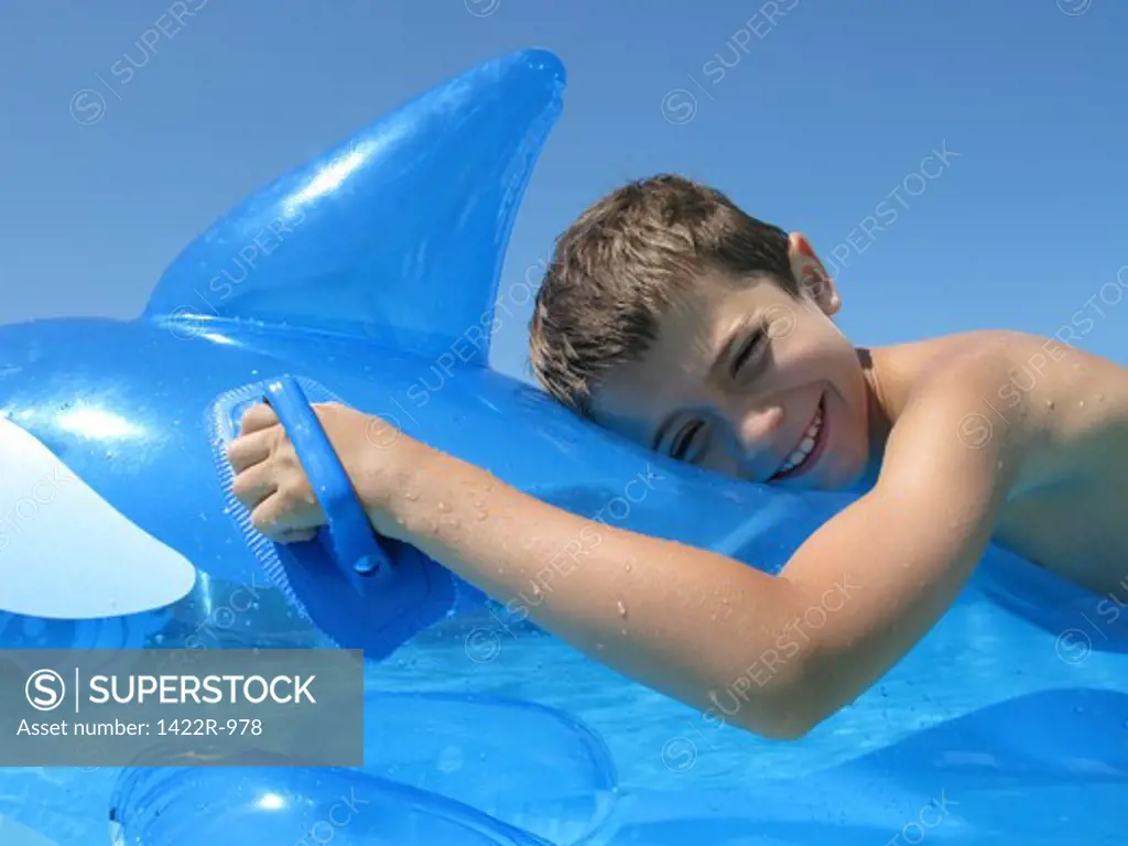 Boy on an inflatable fish in a swimming pool
