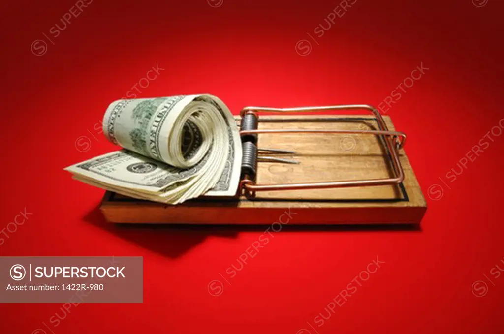 Wooden mousetrap with roll of US currency as bait