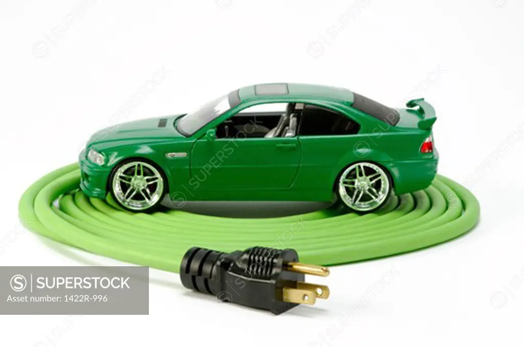 Small green automobile with a coiled green electrical power cord and black plug