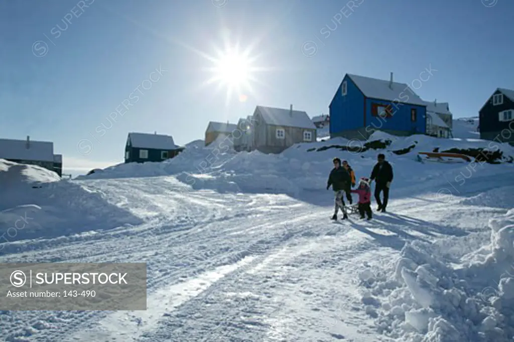 Four people walking on a snow covered road, Ammassalik, Greenland